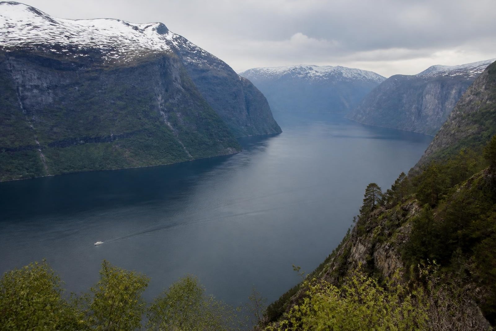 A vast Norwegian fjord seen from above with a tiny vessel far below